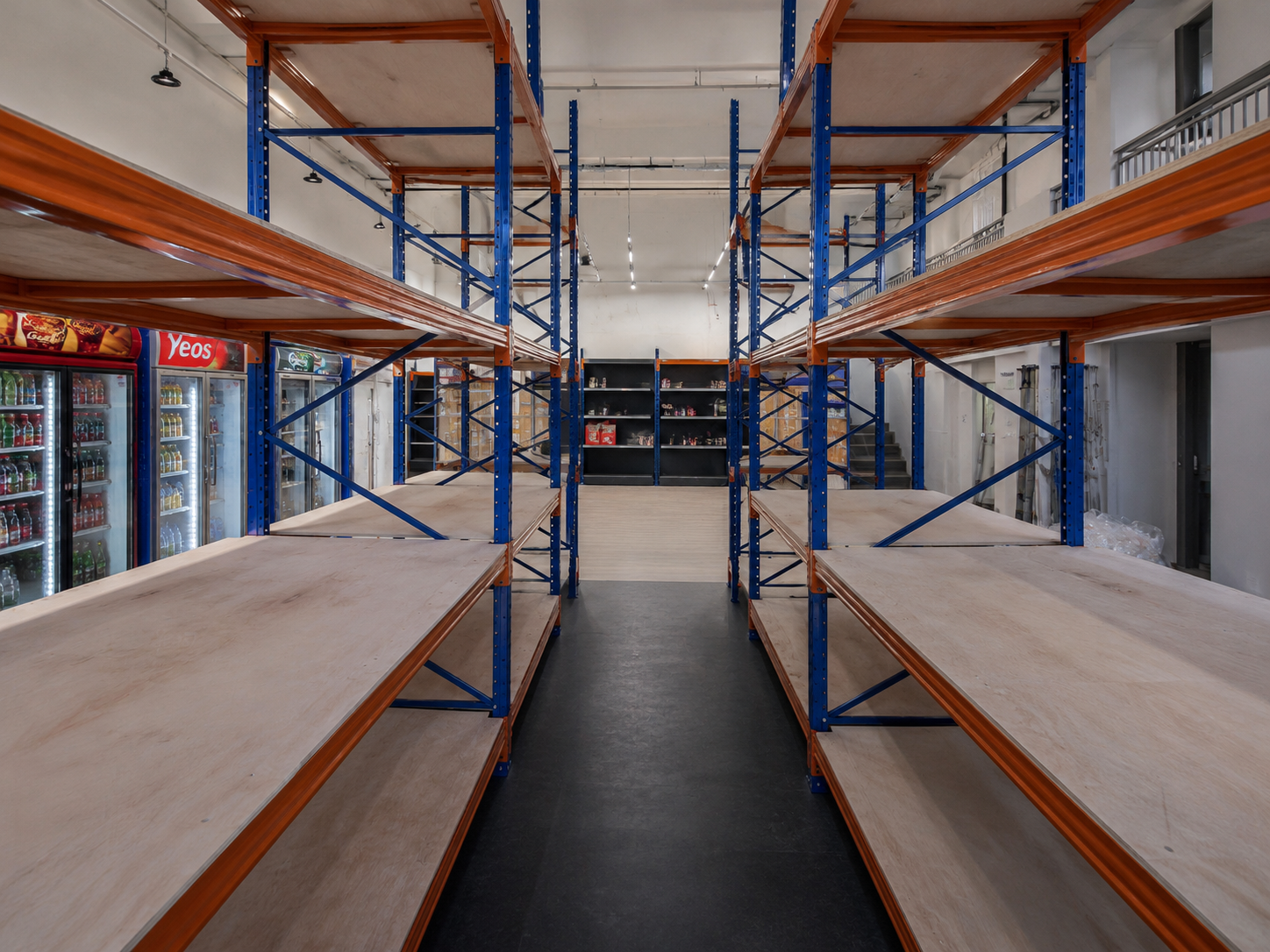 Longspan shelving in Singapore with blue steel uprights, orange beams and plywood shelves viewed along a storage aisle