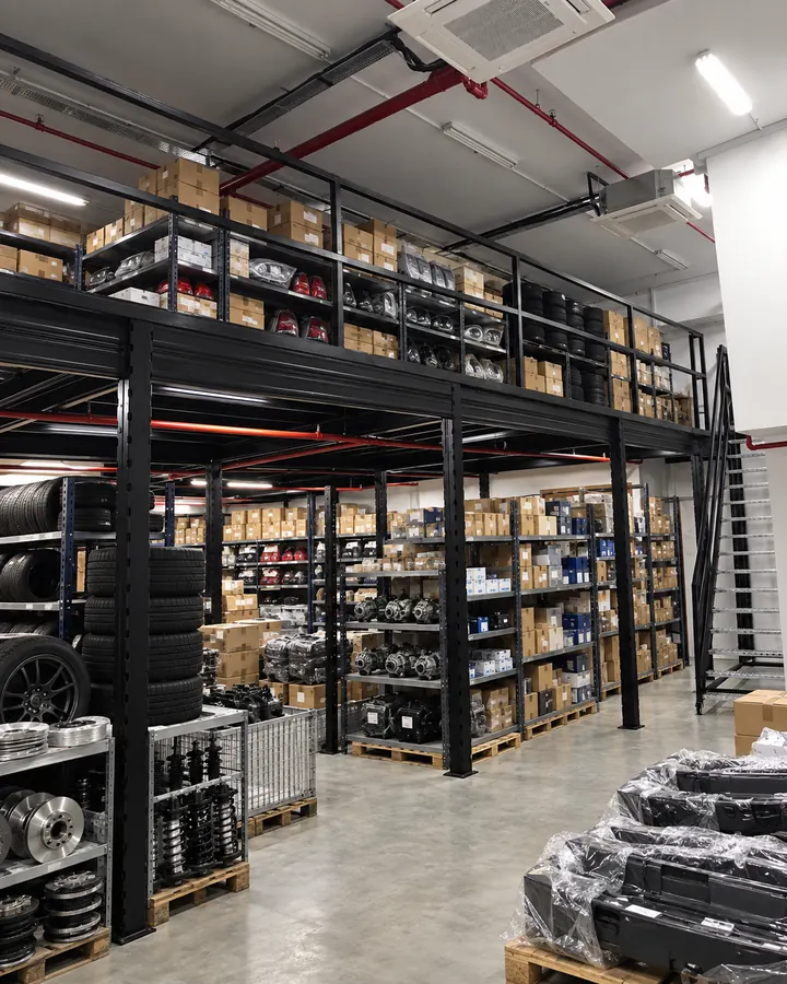 Automotive-parts warehouse mezzanine illustration with tyres, component cartons and spare-parts storage above organised stock below.